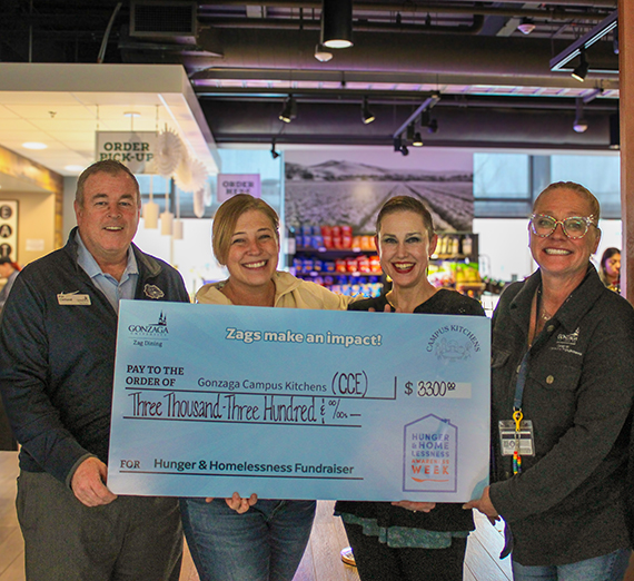 A female student in graduation cap and gown holds her degree over her head. 